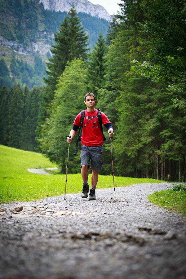 active handsome young man nordic walking/hiking in mountains, enjoying the outdoors