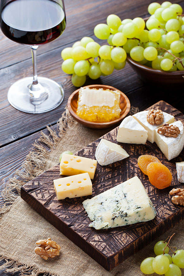 Red wine in glass with cheese, honey, nuts and grape